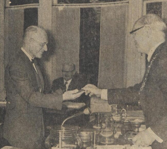 Burgemeester dr. P. D. ff. Peereboom Voller (rechts) overhandigt de zilveren penning van de gemeente Bloemendaal aan de hoofdambtenaar Ch. Lebeau, die 1 november met pensioen gaat.
              <br/>
              Nieuwe Haarlemsche courant, 23 oktober 1964