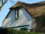 De linker topgevel is bekleed met planken in sierpatroon en voorzien van een uitspringend ladderraampje op een console.
<br/>
Gert-Jan Lobbes, 2024