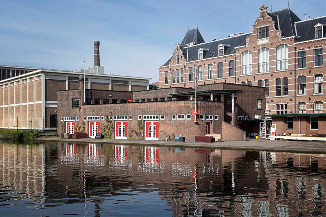 Het verenigingsgebouw gezien vanaf de overkant van het Rijn-Schiekanaal.
              <br/>
              Roel Siebrand, 2021