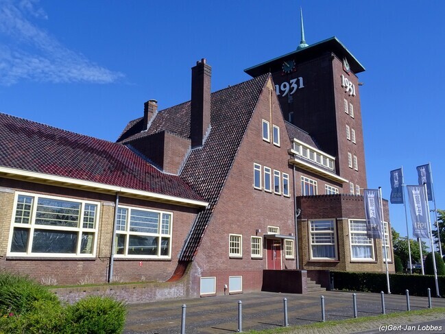 De voorbouw met toren ligt aan een pleintje.
              <br/>
              Gert-Jan Lobbes, 2023